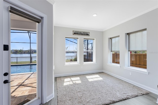 unfurnished room featuring a water view, ornamental molding, wood finished floors, recessed lighting, and baseboards