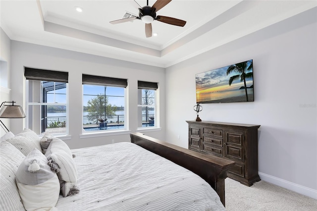 bedroom featuring a tray ceiling, baseboards, light colored carpet, and crown molding