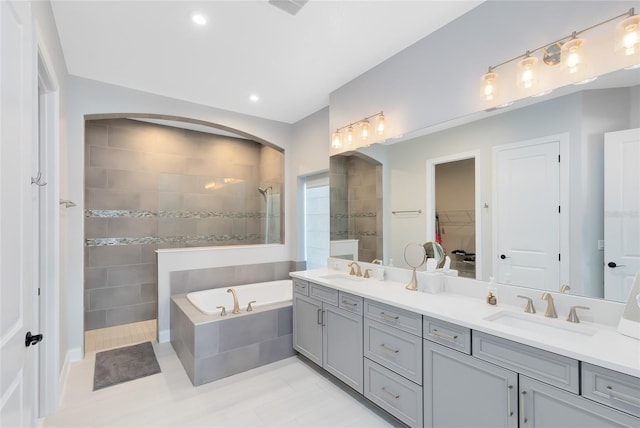 bathroom with a sink, walk in shower, a bath, and double vanity