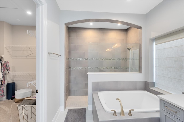 bathroom featuring a spacious closet, a walk in shower, a bath, and vanity