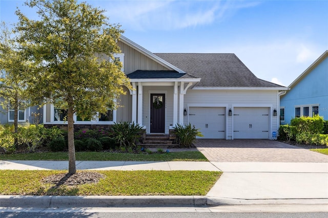 view of front of home featuring a garage, decorative driveway, board and batten siding, and a shingled roof