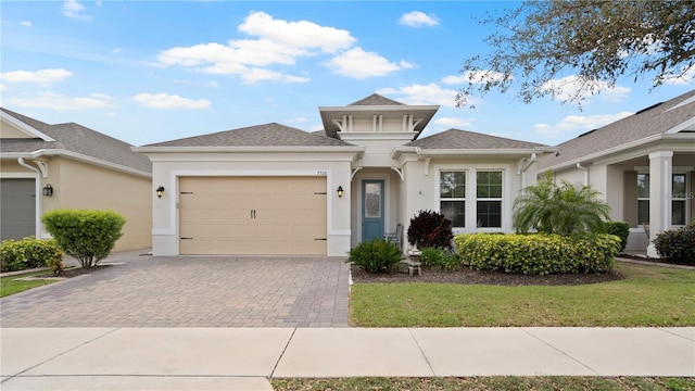 view of front of property featuring stucco siding, a shingled roof, decorative driveway, and a garage