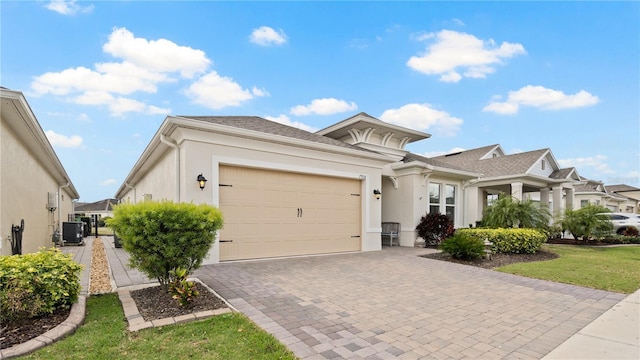 view of front of house with central air condition unit, decorative driveway, an attached garage, and stucco siding