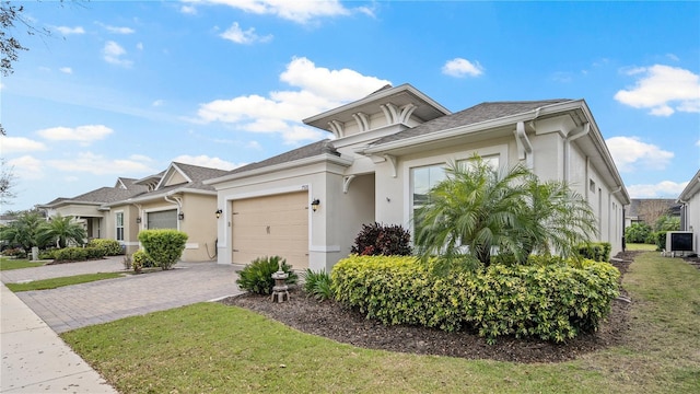 view of front facade featuring decorative driveway, a front yard, an attached garage, and stucco siding