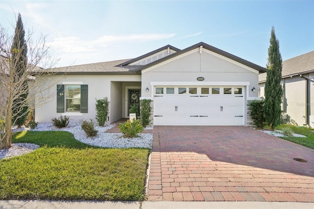 ranch-style home with a shingled roof, a front yard, stucco siding, decorative driveway, and a garage