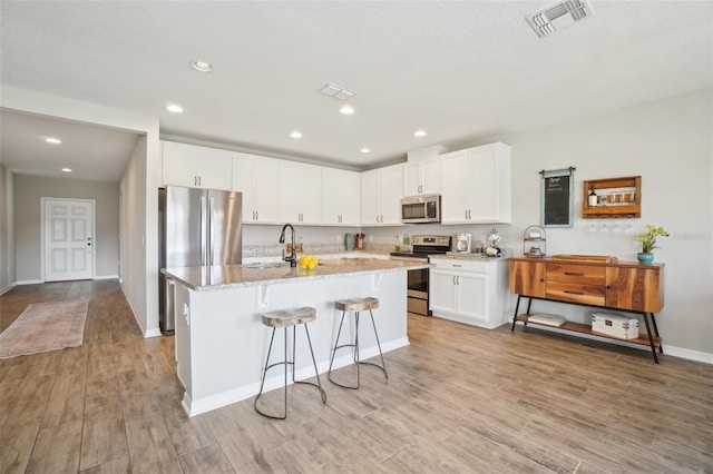 kitchen featuring light wood finished floors, visible vents, white cabinets, and appliances with stainless steel finishes