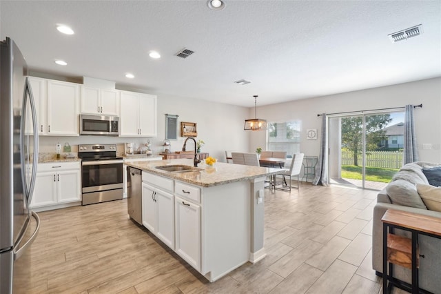 kitchen featuring visible vents, a sink, white cabinets, appliances with stainless steel finishes, and light wood-type flooring