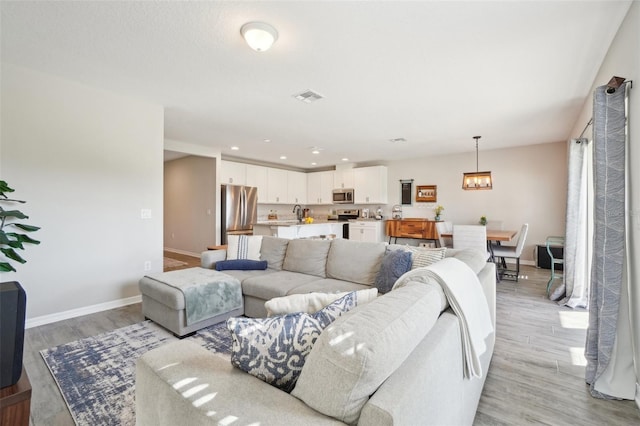 living room with recessed lighting, visible vents, baseboards, and light wood-style floors