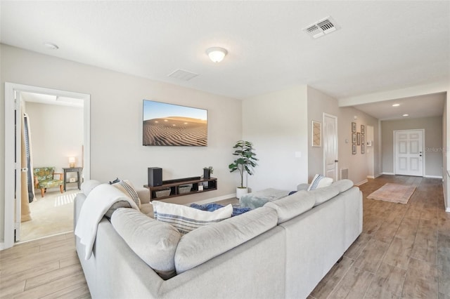 living room featuring baseboards, visible vents, and light wood finished floors