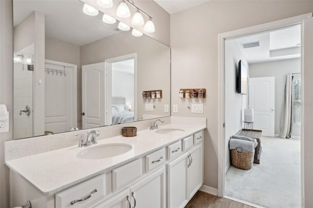 ensuite bathroom featuring double vanity, visible vents, ensuite bathroom, and a sink