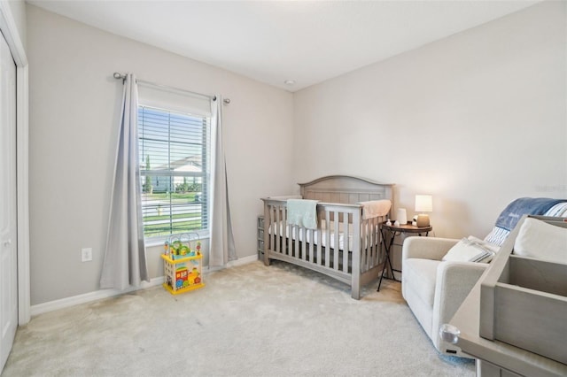 bedroom with a nursery area, baseboards, and carpet floors