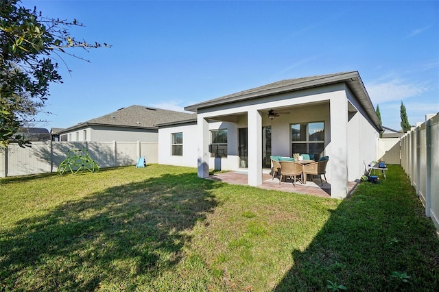 rear view of house with a ceiling fan, a fenced backyard, stucco siding, a patio area, and a lawn