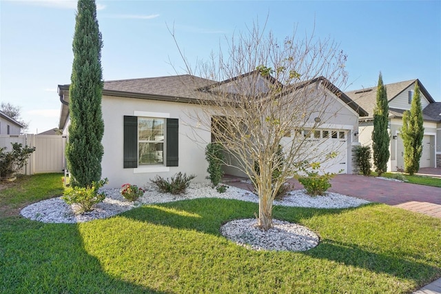 ranch-style house with stucco siding, decorative driveway, fence, a front yard, and a garage