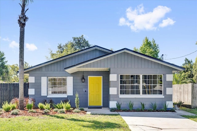 view of front of house featuring concrete block siding, fence, and a front lawn