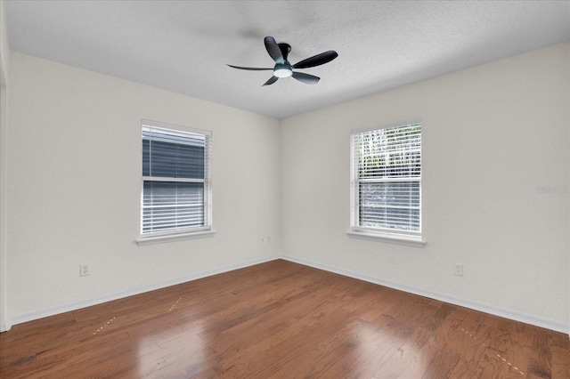 spare room featuring ceiling fan, baseboards, a textured ceiling, and wood finished floors