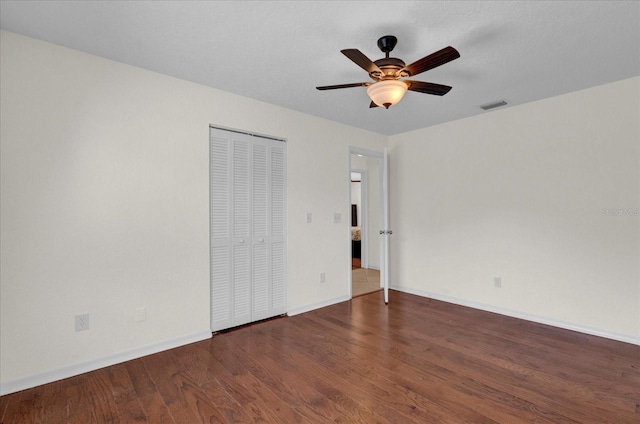 empty room with ceiling fan, visible vents, baseboards, and wood finished floors