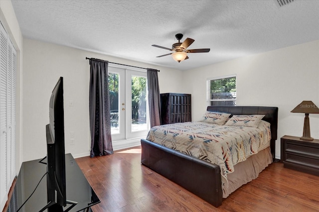 bedroom with a ceiling fan, multiple windows, wood finished floors, and french doors