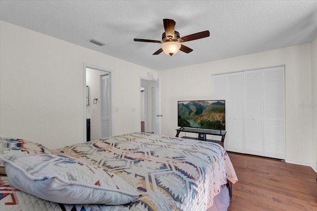 bedroom featuring visible vents, ceiling fan, wood finished floors, a closet, and a textured ceiling