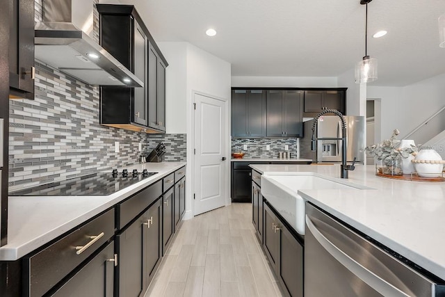 kitchen featuring a sink, stainless steel appliances, wall chimney exhaust hood, and light countertops