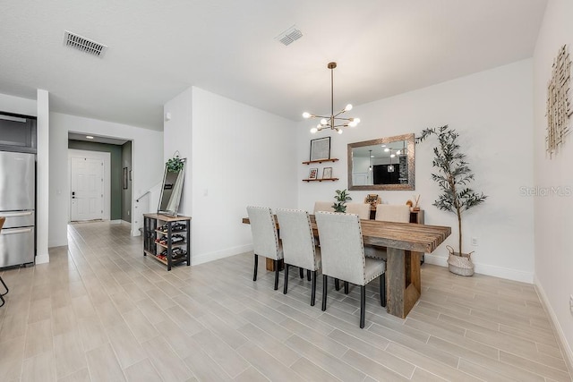 dining space featuring an inviting chandelier, baseboards, visible vents, and light wood finished floors