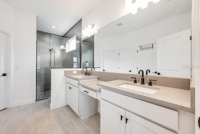 full bathroom featuring double vanity, walk in shower, baseboards, and a sink