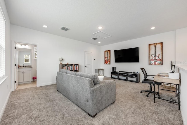 living area featuring light carpet, visible vents, recessed lighting, and attic access