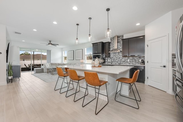 kitchen with visible vents, a breakfast bar, stainless steel appliances, decorative backsplash, and wall chimney exhaust hood