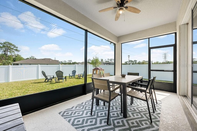 sunroom featuring ceiling fan and a water view