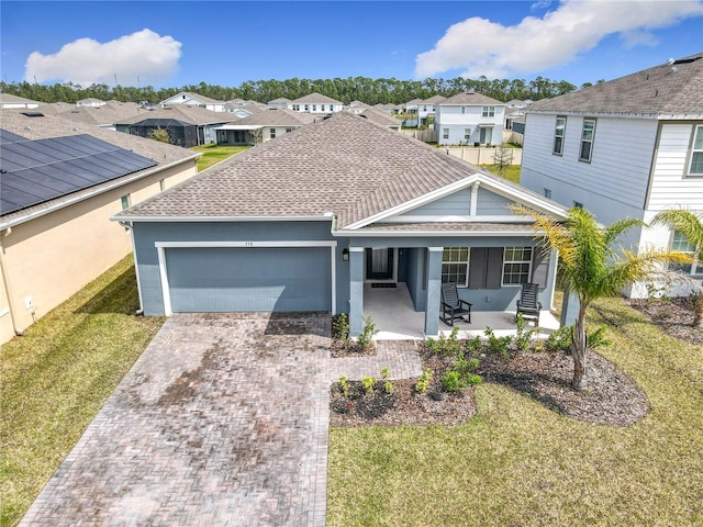 single story home featuring a residential view, an attached garage, decorative driveway, and a front yard