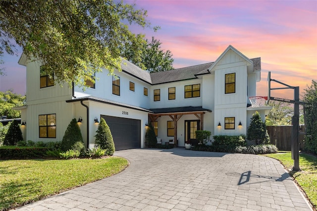 modern farmhouse with board and batten siding, fence, decorative driveway, a garage, and a yard