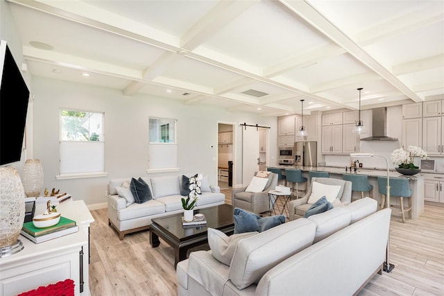 living area with beam ceiling, coffered ceiling, light wood-type flooring, and a barn door