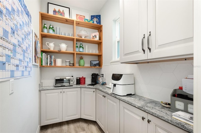 kitchen featuring light stone countertops, open shelves, decorative backsplash, white cabinets, and light wood-style floors