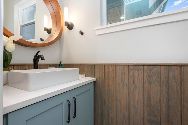 bathroom featuring vanity, wood walls, and wainscoting