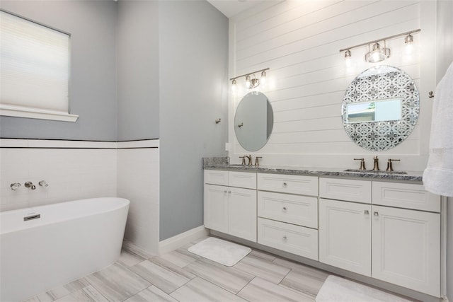 bathroom with a sink, a freestanding bath, and double vanity