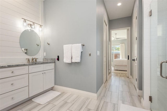 ensuite bathroom featuring baseboards, vanity, ensuite bath, and a shower stall