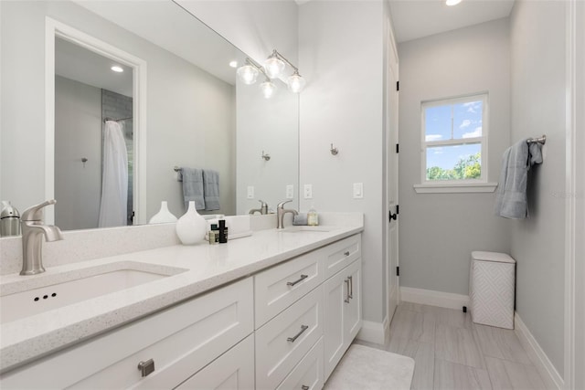 bathroom with a sink, baseboards, recessed lighting, and double vanity