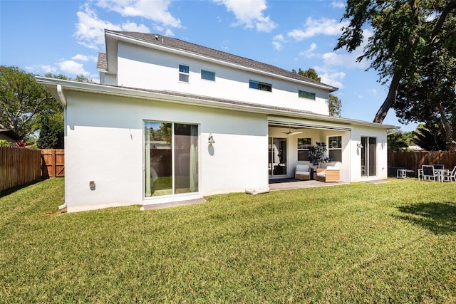 back of house with a yard, stucco siding, and a fenced backyard