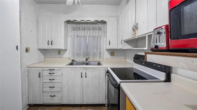 kitchen with white cabinetry, light countertops, electric range oven, and a sink