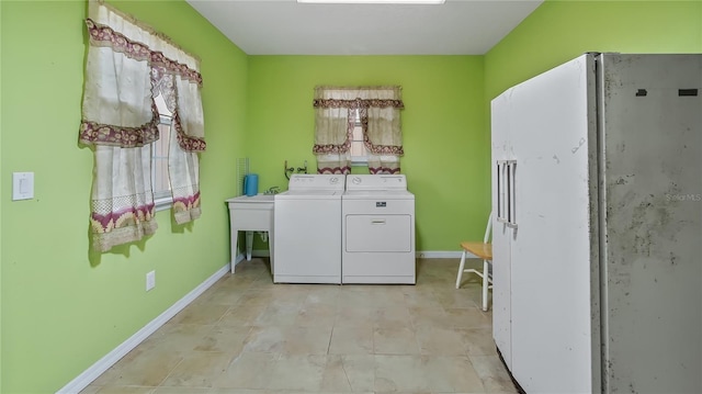 clothes washing area featuring a sink, laundry area, baseboards, and washing machine and clothes dryer