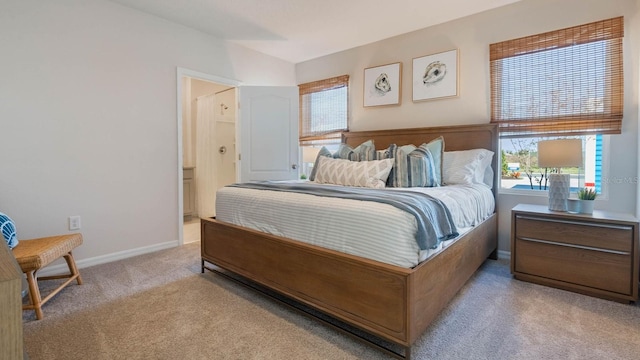 carpeted bedroom featuring vaulted ceiling, baseboards, and connected bathroom