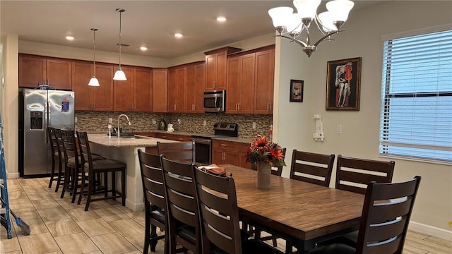 kitchen with a breakfast bar, a kitchen island with sink, a sink, stainless steel appliances, and decorative backsplash