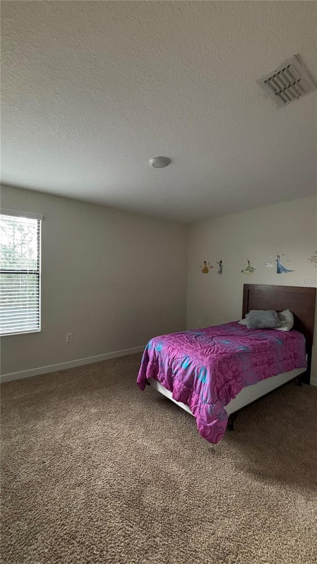 carpeted bedroom featuring baseboards, visible vents, and a textured ceiling