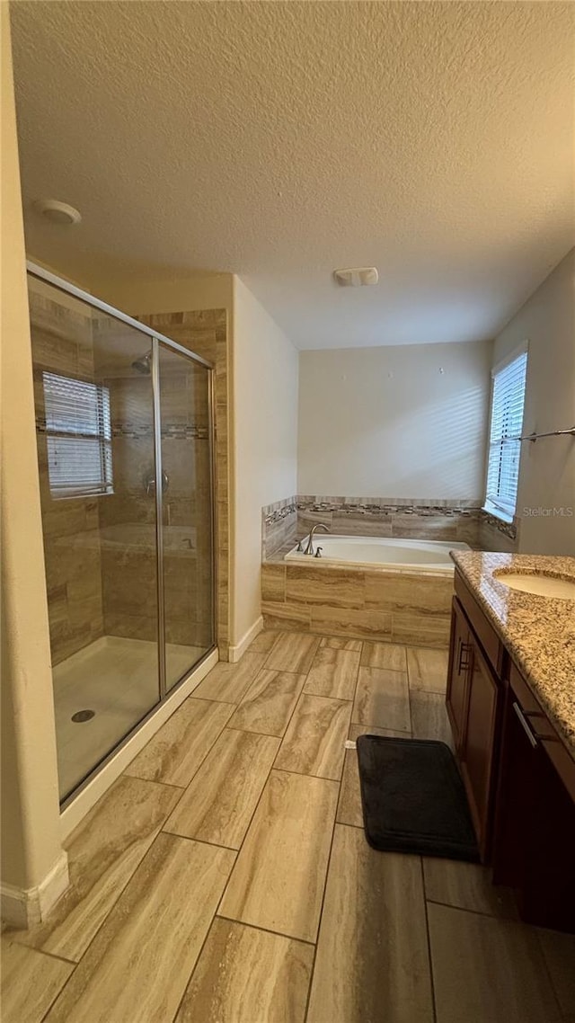 bathroom featuring a garden tub, a textured ceiling, vanity, a shower stall, and wood tiled floor