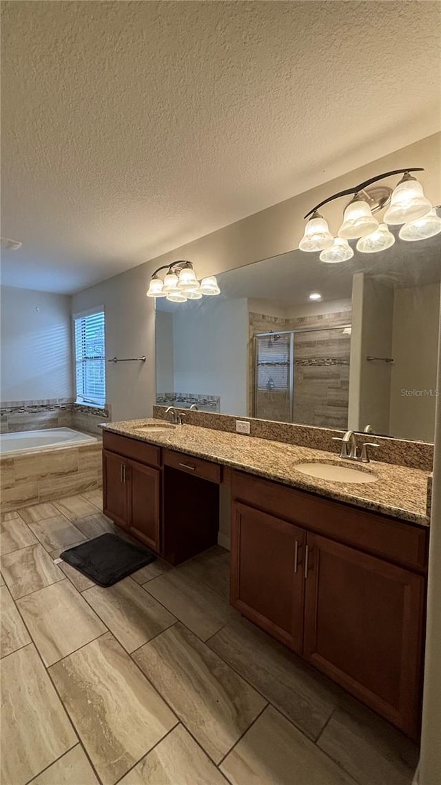 full bathroom featuring a textured ceiling, a stall shower, vanity, and a bath