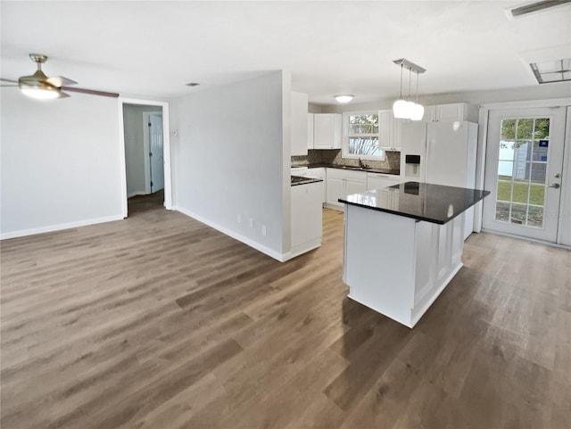 kitchen featuring dark countertops, white cabinets, light wood-style floors, and white fridge with ice dispenser