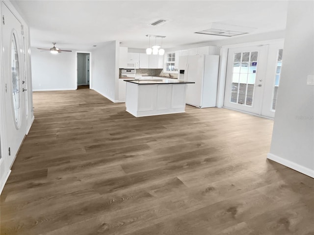 kitchen featuring visible vents, dark countertops, open floor plan, white appliances, and white cabinets