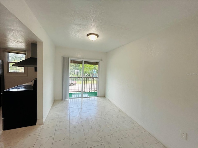 empty room with baseboards, a textured ceiling, and marble finish floor