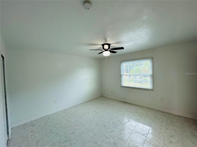 spare room featuring baseboards, marble finish floor, and a ceiling fan