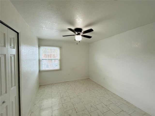 unfurnished room featuring baseboards, a textured ceiling, marble finish floor, and ceiling fan