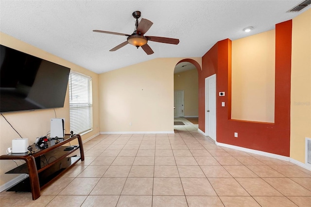 living room with visible vents, vaulted ceiling, arched walkways, light tile patterned flooring, and a textured ceiling